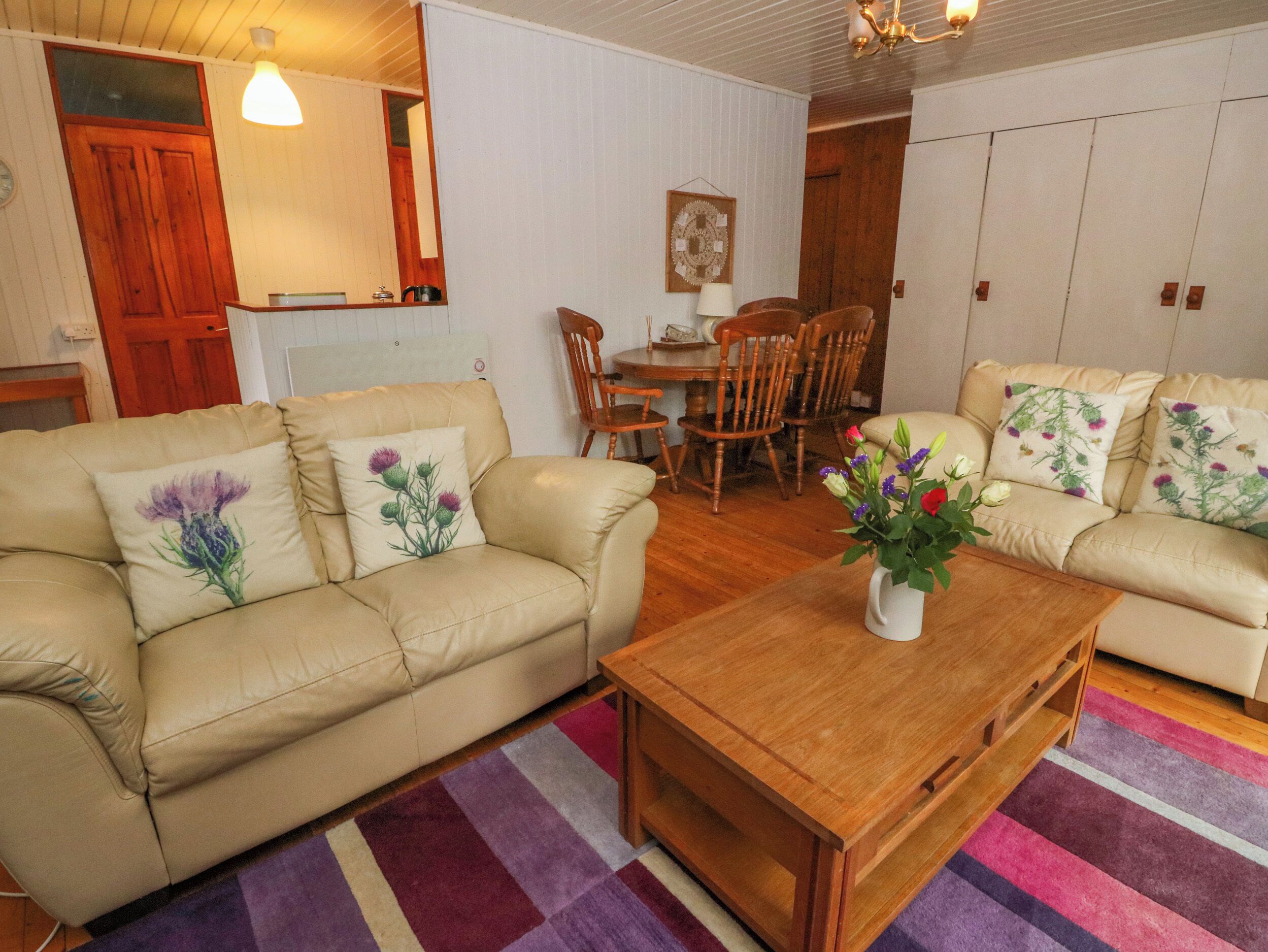 Una sala de estar con dos sofás beige, una mesa de centro de madera y una zona de comedor con sillas y una mesa de madera.