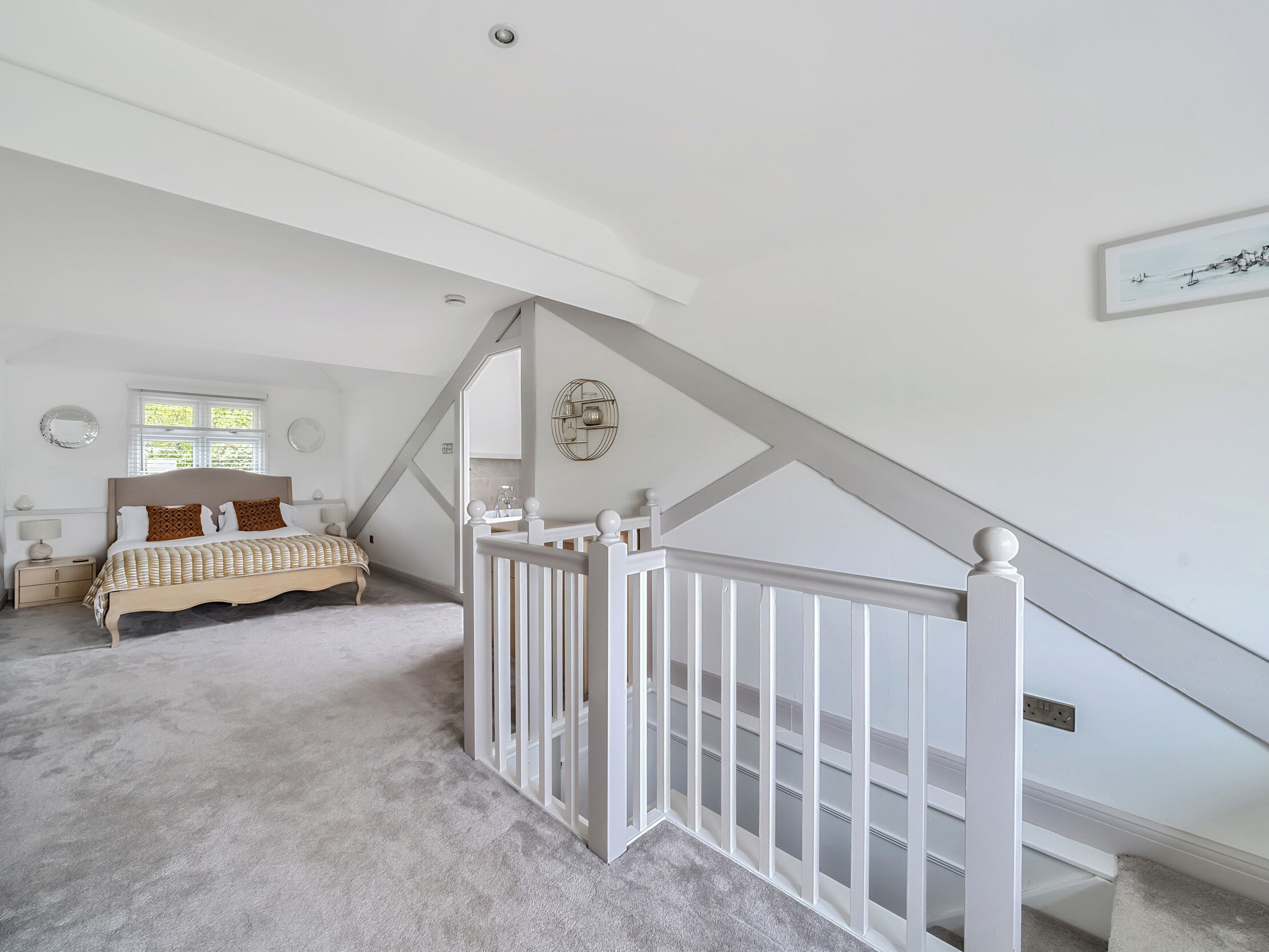 A bedroom with a bed, a nightstand, a dresser, a window, and a staircase.