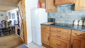 A kitchen with wooden cabinets, a white refrigerator, a tiled backsplash, and a dining area with a table and chairs.