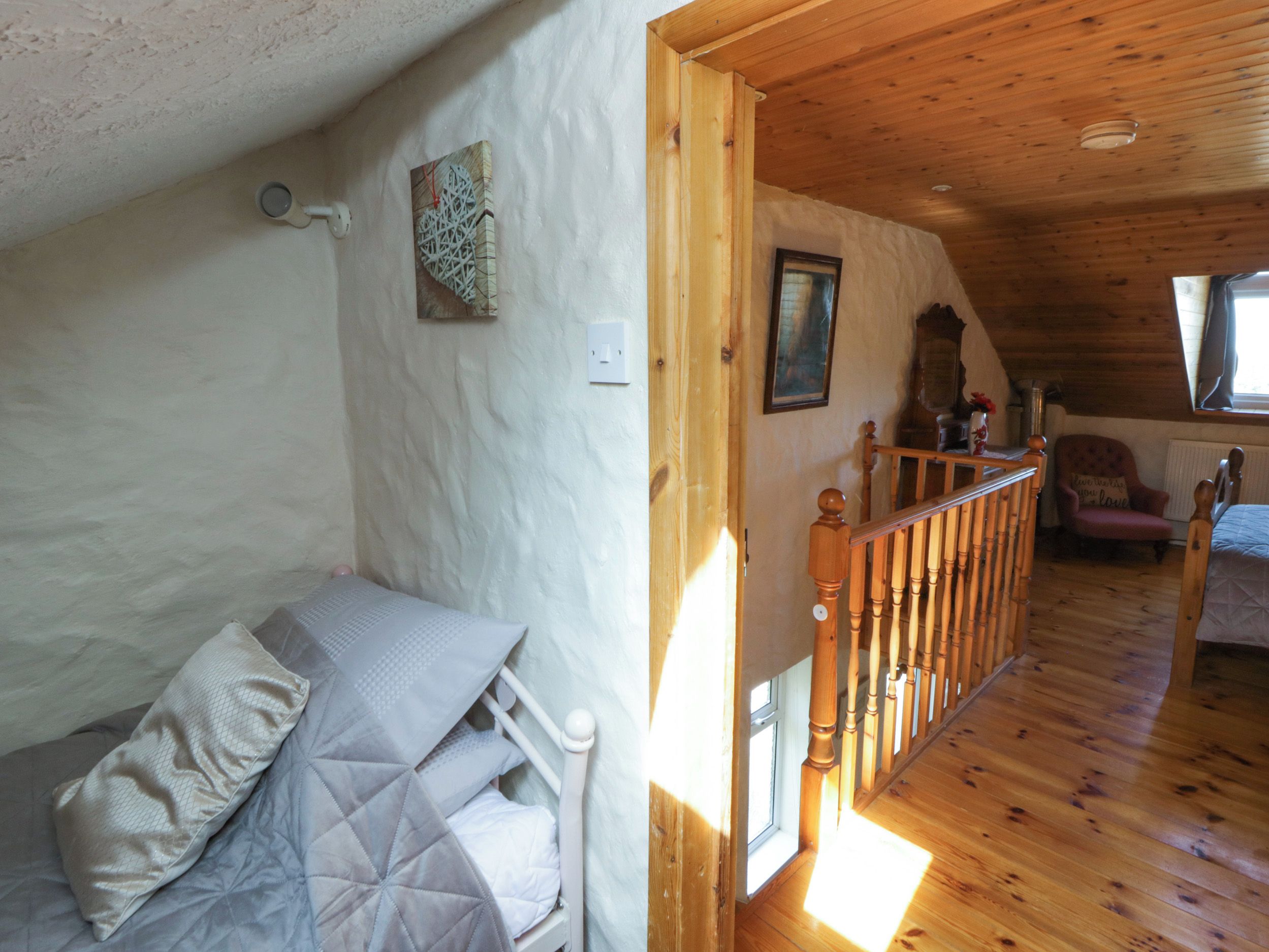 Un dormitorio con cama, una escalera de madera, una silla y un cuadro en la pared.