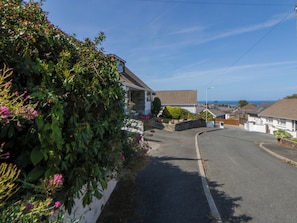 A residential street with houses, a clear sky, and a view of the sea.