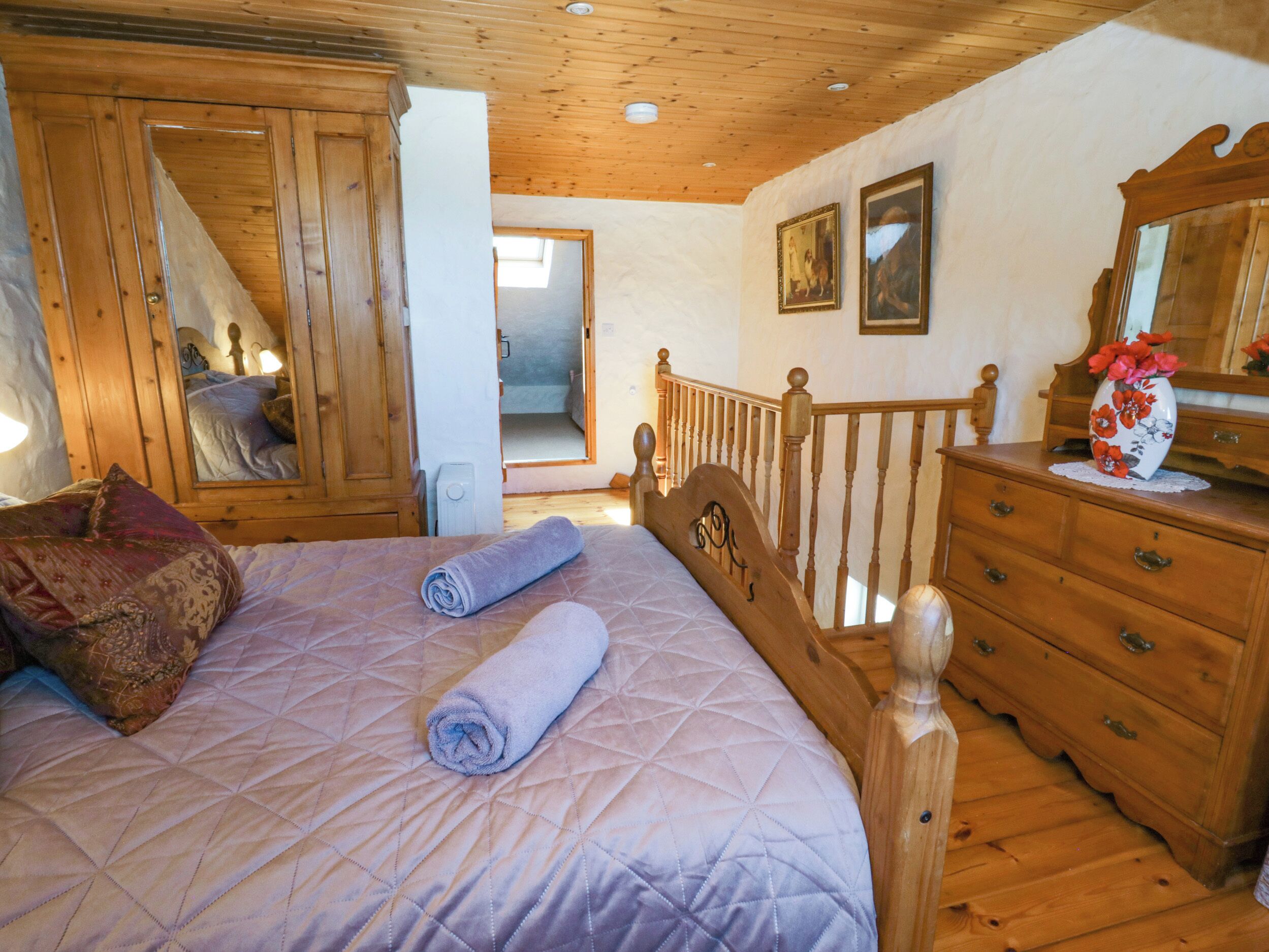 A bedroom with a wooden bed, a dresser, and a mirror.