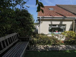 Een woongebouw met een pannendak, een raam met een bloempot en een houten bankje.