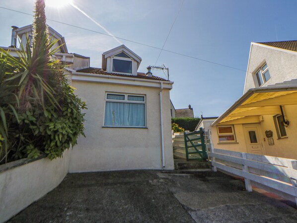 A residential property with a paved driveway, a gated entrance, and a small garden area.