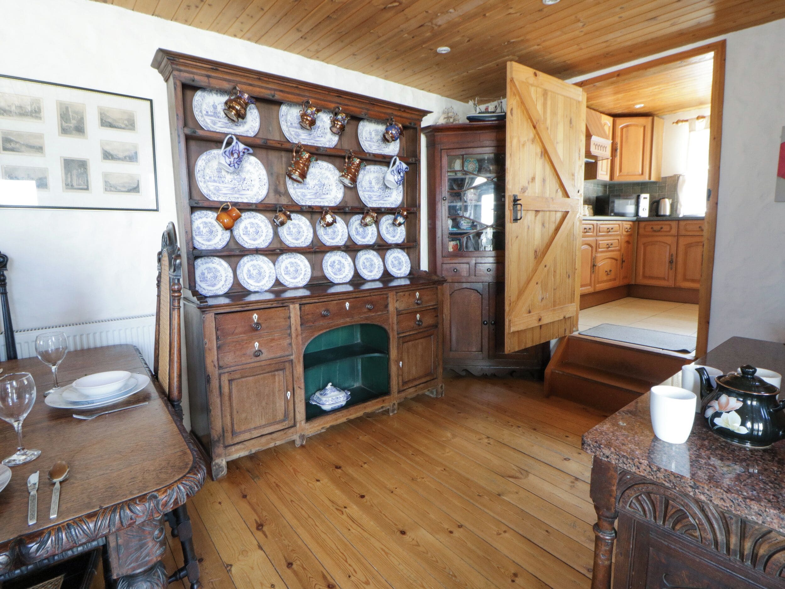 A traditional kitchen with wooden cabinets, a dining table set with plates and glasses, and a coffee table with a teapot.