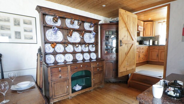 A traditional kitchen with wooden cabinets, a dining table set with plates and glasses, and a coffee table with a teapot.