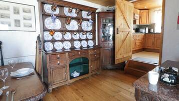 A traditional kitchen with wooden cabinets, a dining table set with plates and glasses, and a coffee table with a teapot.