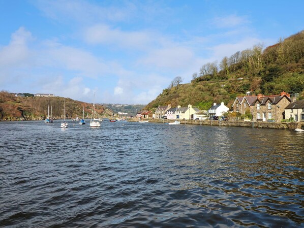 Een rustige rivier met bootjes, een stenen kadaster en huizen langs de oever.