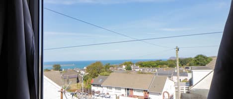 Un barrio residencial con casas, cielo despejado y vista al mar.