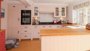 A kitchen with white cabinets, a black oven, a microwave, and a wooden countertop. - 6 Willows Green (Aldeburgh)