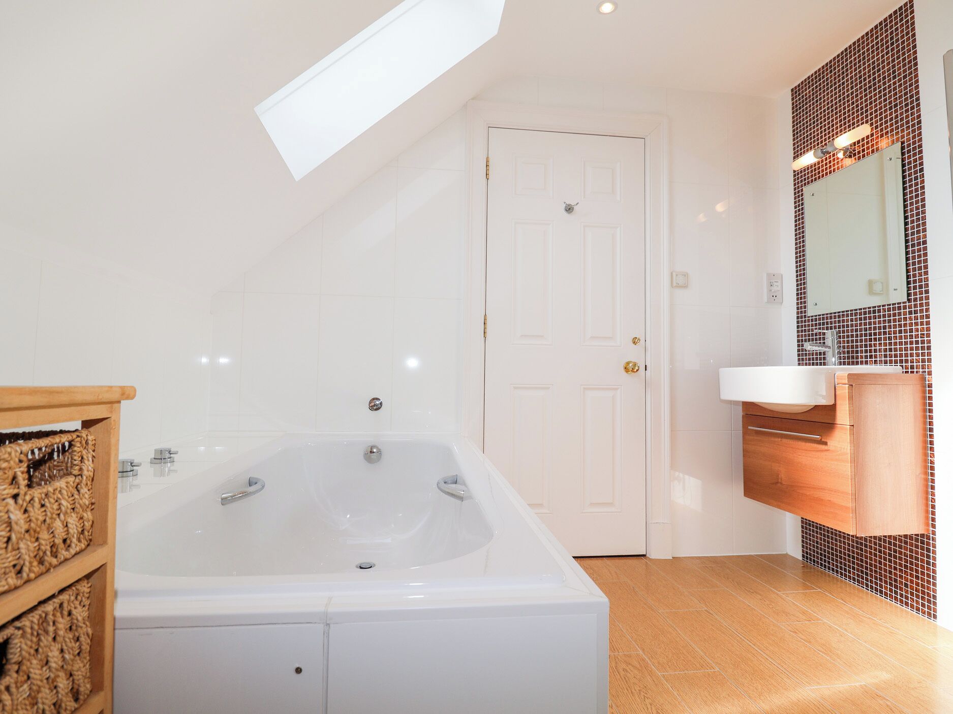 A modern bathroom with a freestanding bathtub, a wooden vanity, and a large mirror.