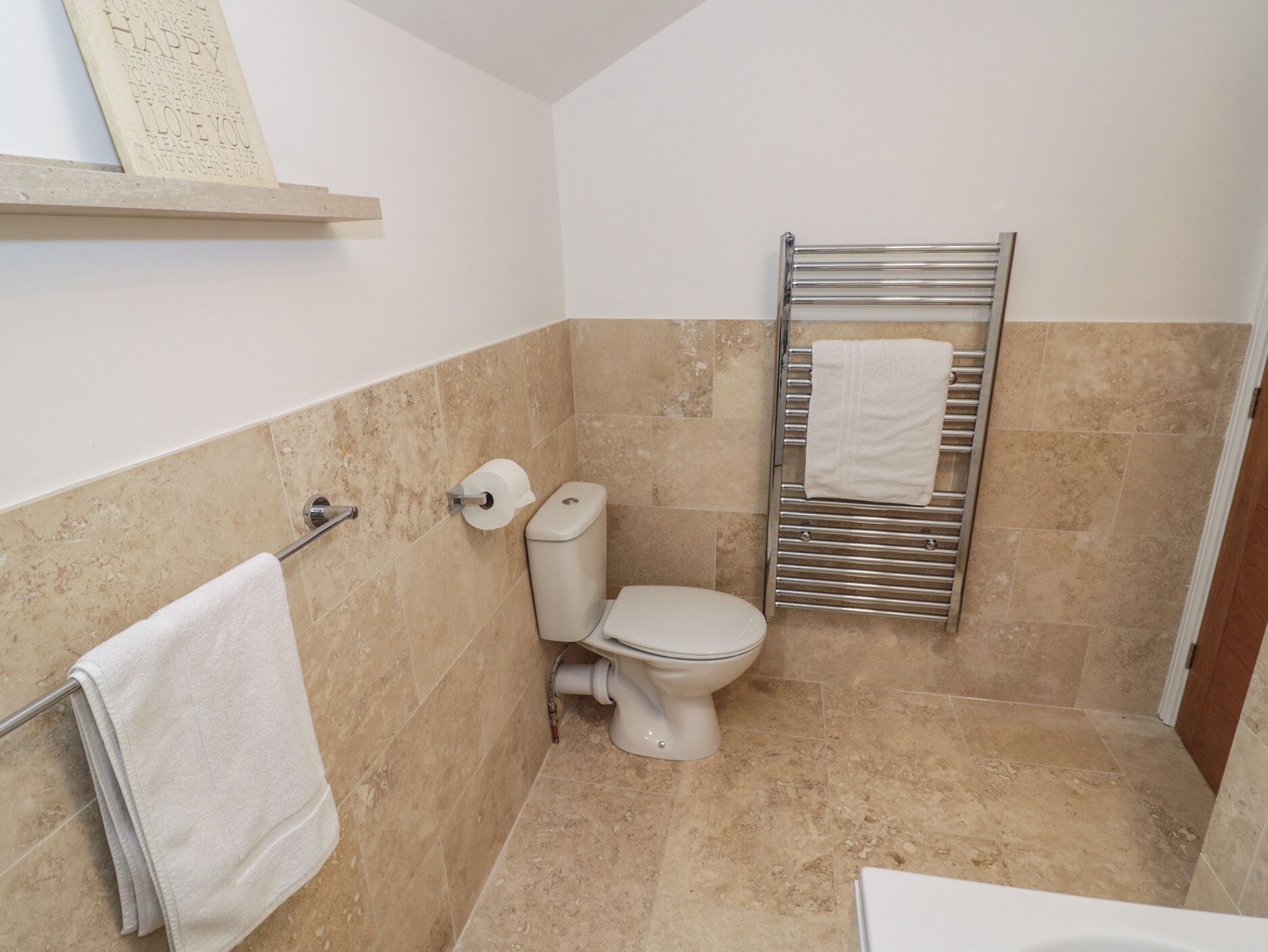 Ein Badezimmer mit Toilette, Handtuchhalter und einem Handtuch.