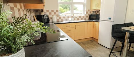Eine Küche mit Holzausstattung, einer schwarzen Arbeitsplatte, einem weißen Kühlschrank und einem Blumentopf.