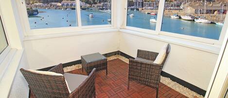 A corner room with wicker furniture and a view of a harbor.