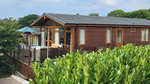 A wooden cabin with a porch, large windows, and a covered outdoor seating area. - Matilda Lodge (Plymouth)