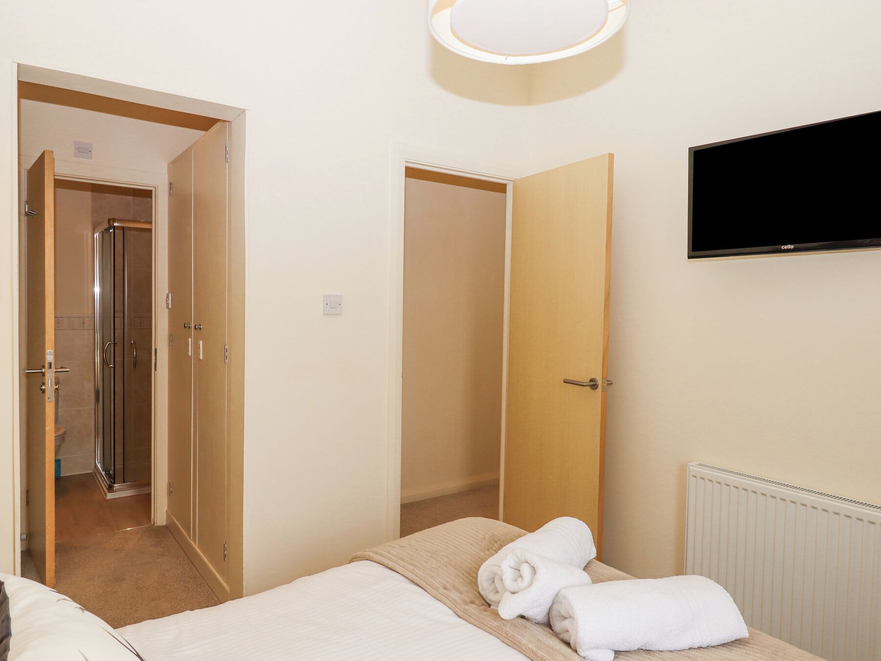 Ein Hotelzimmer mit Bett, Fernseher, Dusche und einer Tür zu einem weiteren Raum.