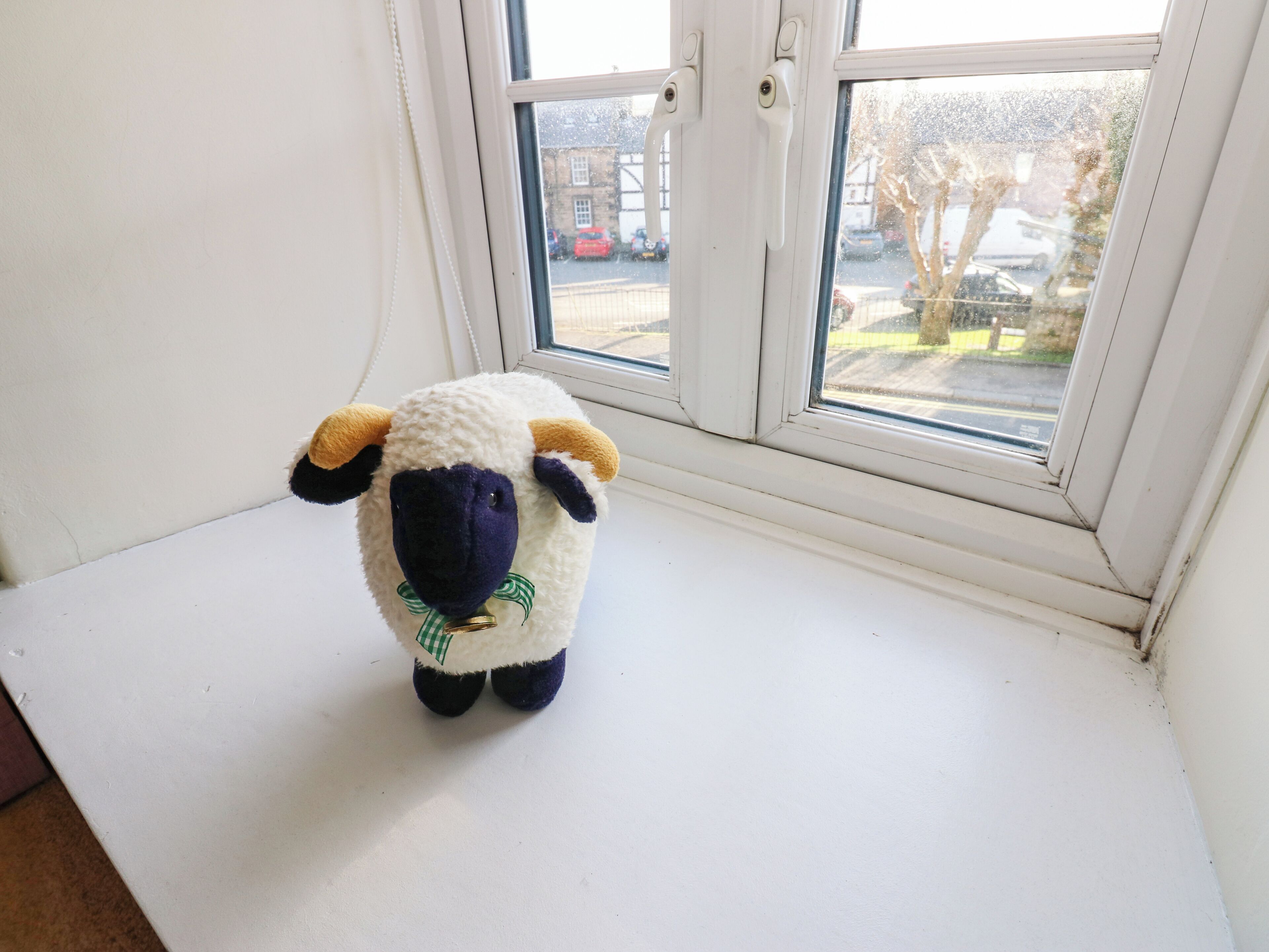 Un cordero de peluche sobre un alféizar blanco.