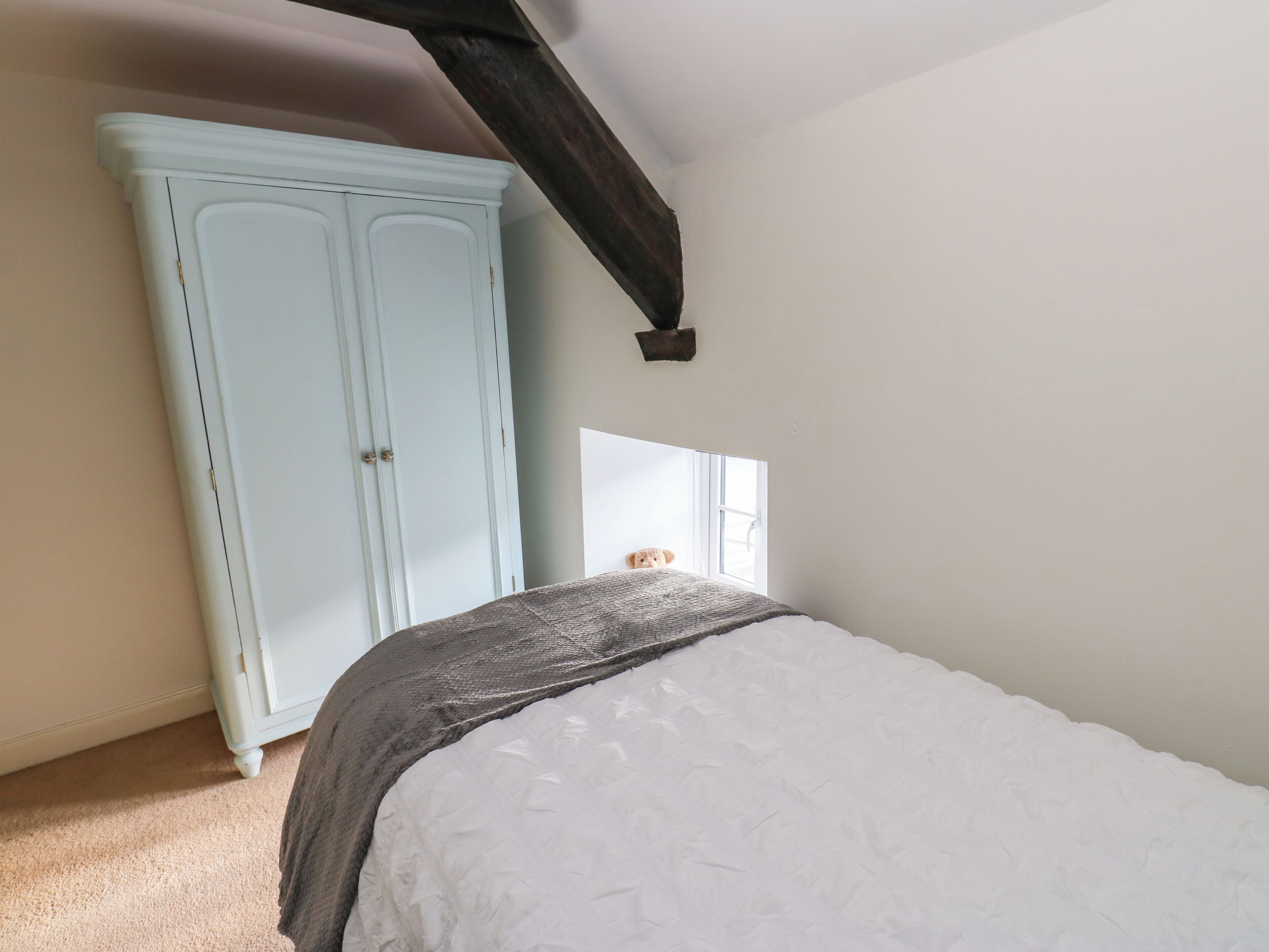 A bedroom with a bed, a wardrobe, and a window.