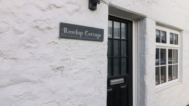 A white cottage with a black door and a sign reading "Rosehip Cottage". - Rose Hip Cottage (Hexham)