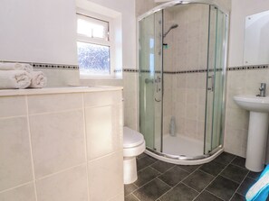 Een badkamer met een douchecabine van glas, een toilet en een wastafel.