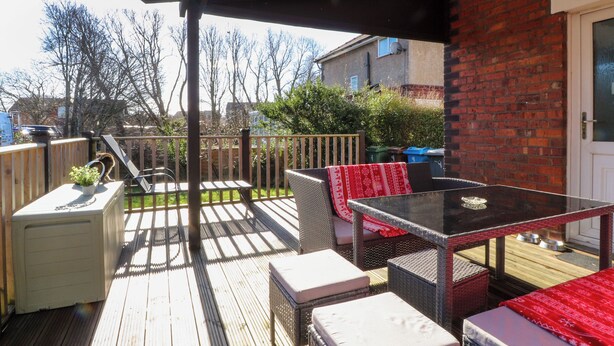 A covered outdoor patio with a table and chairs, a small white heater, and a wooden deck. - Lytham House (Lytham St. Anne's)