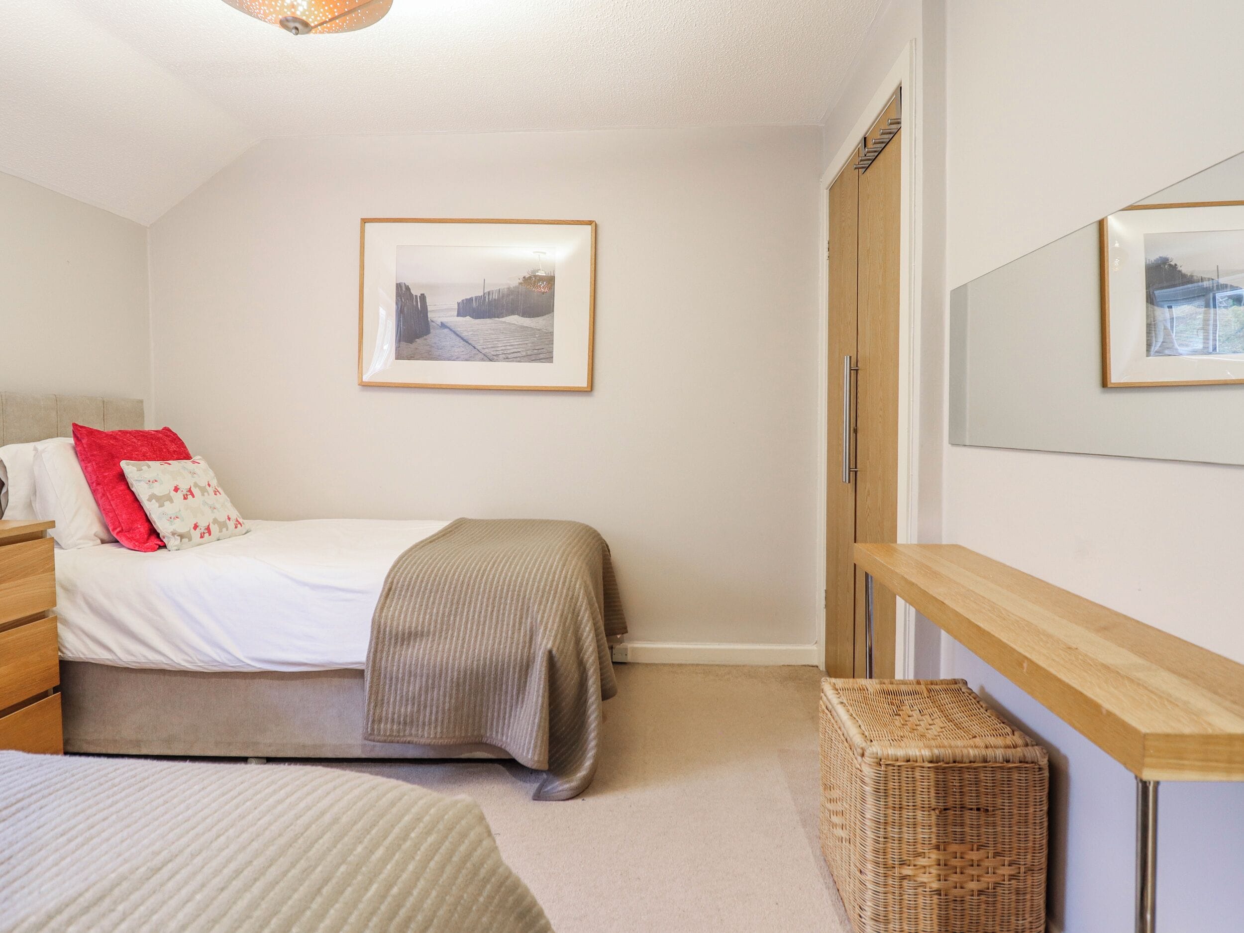 Une chambre à coucher comprenant un lit, une commode, une table de chevet, un miroir et un tableau encadré accroché au mur.