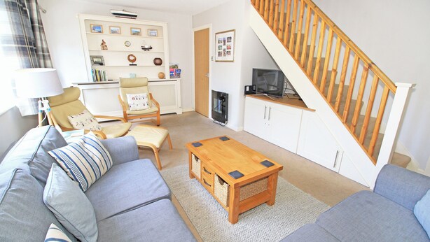 A living room with a sofa, armchair, coffee table, and a staircase. - Green Cottage (Porthmadog)
