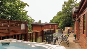 A hot tub area with a wooden deck, outdoor furniture, and a wooden fence. - Templar Rise 16 - Devon Comfort (Newton Abbot)