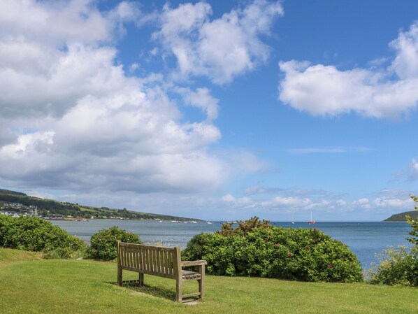 A bench in a grassy area with a view of the sea and boats. - Lodge 6 - "alder" (Isle of Arran)