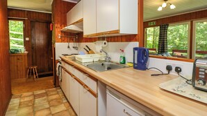 A compact kitchen with wooden cabinets, a sink, and a countertop. - Lodge 6 - "alder" (Isle of Arran)