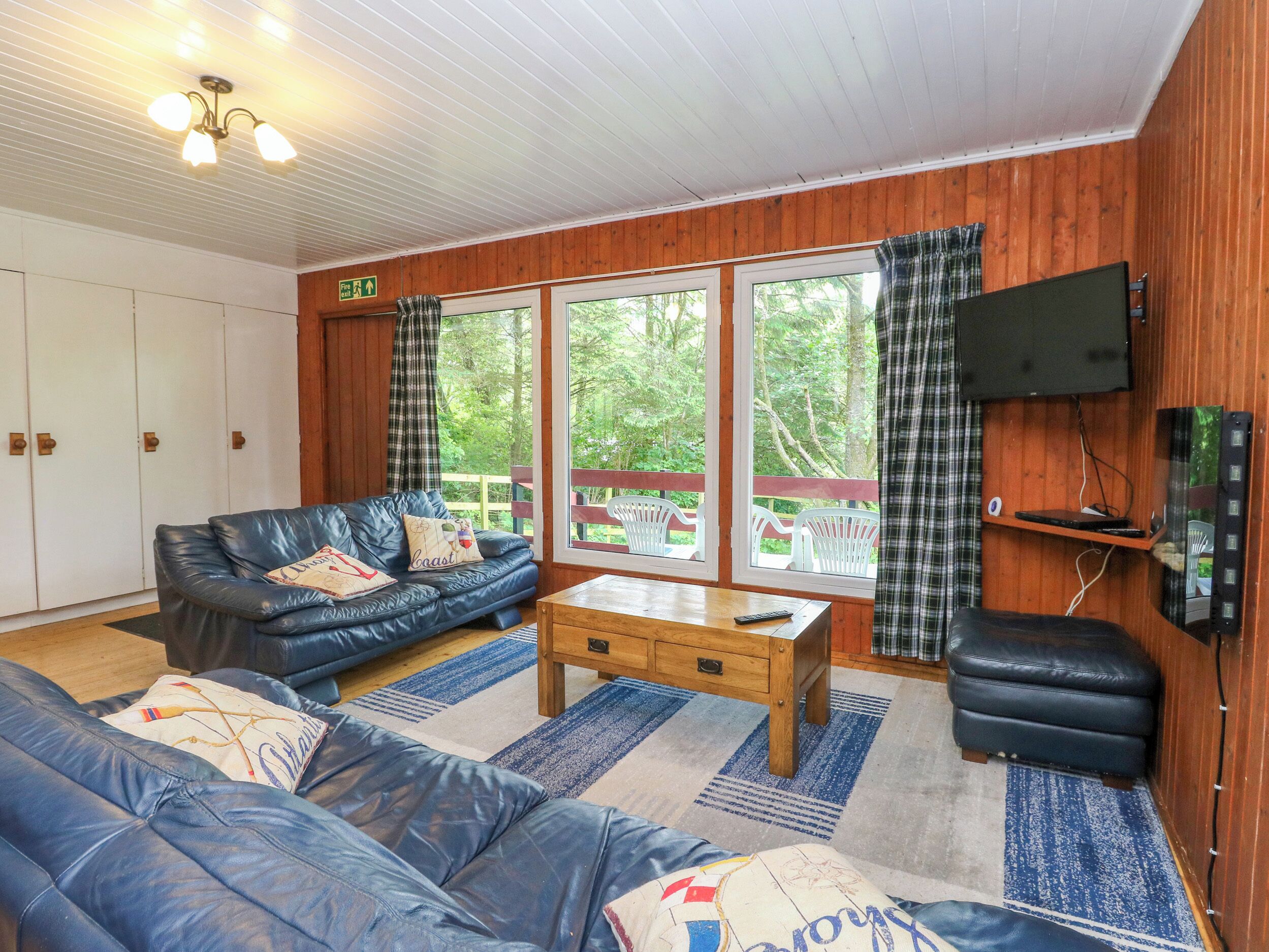 Ein gemütliches Zimmer mit einem blauen Ledersofa, einem Holztisch und einem an der Wand befestigten Fernseher.