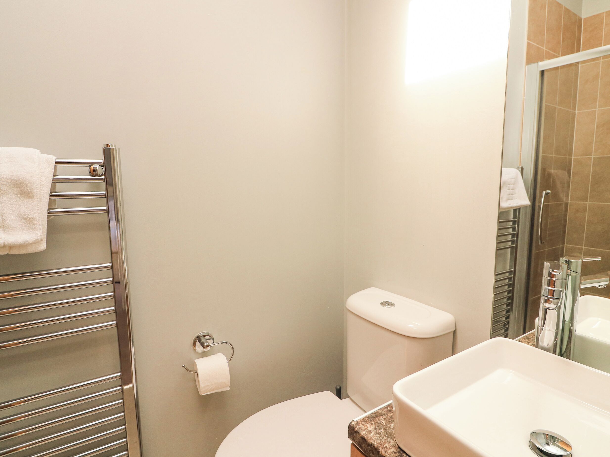 Un baño con inodoro, lavamanos y un perchero para toallas.