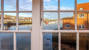 A view through a window with a clear reflection of a harbor, buildings, and a red-roofed structure.