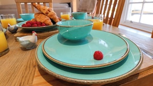 A breakfast setting with croissants, raspberries, and a bowl of orange juice on a wooden table.