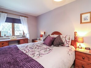 A bedroom with a bed, bedside tables, a window with curtains, and a wall-mounted picture. - Old Farm Cottage (Ilfracombe)