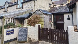 A traditional stone building with a wooden door and a sign indicating 'Old Farm Cottage'. - Old Farm Cottage (Ilfracombe)
