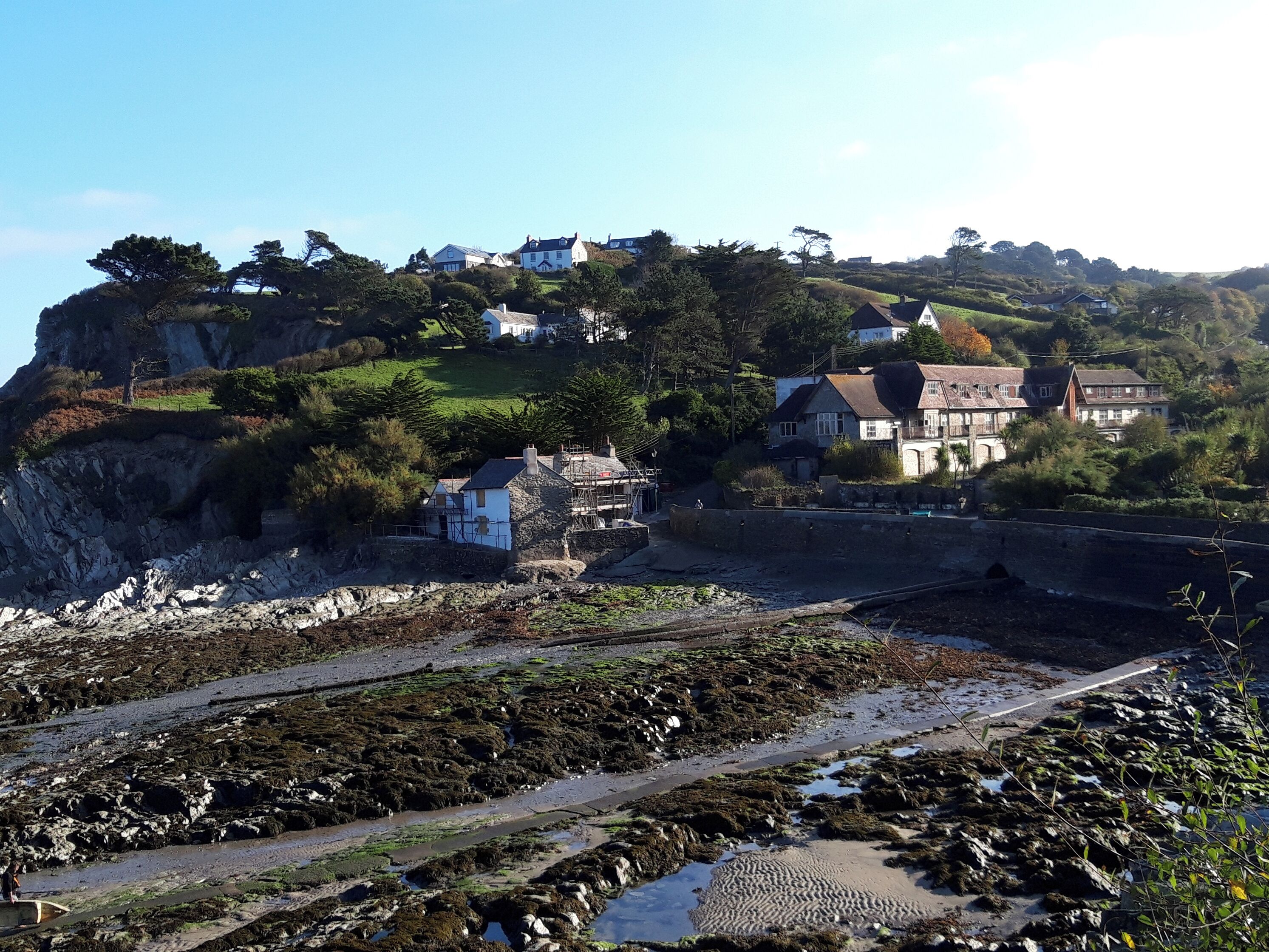 A coastal village with houses on a cliff, a rocky shoreline, and a clear sky.