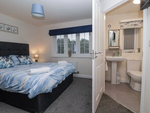 A bedroom with a bed, bedside table, and a window with blinds. - Happy Days (Bridlington)