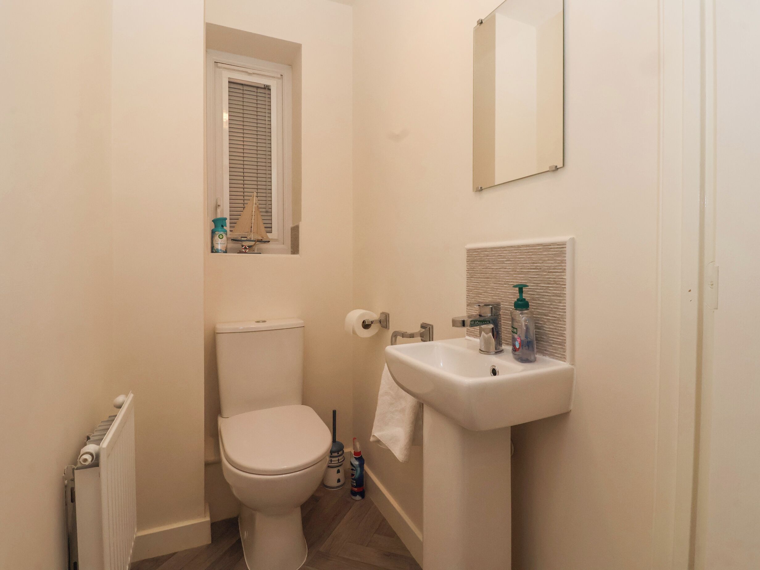 A small bathroom with a toilet, a sink, and a window above the toilet.