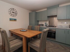 Una cocina moderna con armarios color turquesa, una mesa de comedor de madera y sillas a rayas.