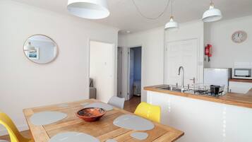 A modern kitchen with a wooden countertop, a sink, and a stove. There is a dining area with a wooden table and chairs.