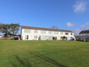 A two-story residential building with a flat roof, large windows, and a front lawn. - Beachcomber (Bude)