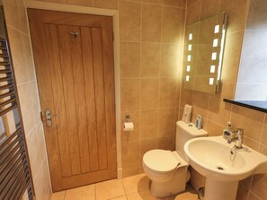 A bathroom with a wooden door, a toilet, a sink, and a mirror. - Fox Howe (Keswick)