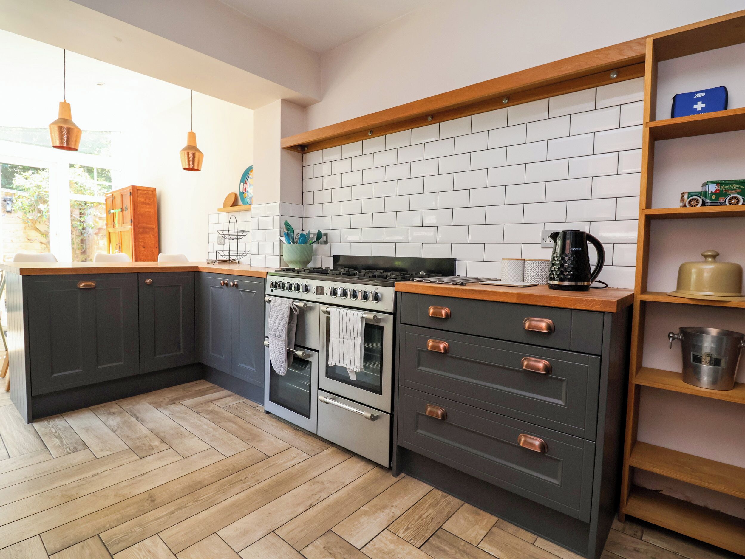 A kitchen with dark cabinets, a white tiled backsplash, a stove, an oven, and a coffee maker.