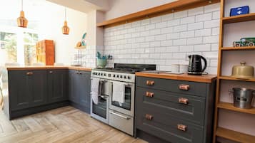 A kitchen with dark cabinets, a white tiled backsplash, a stove, an oven, and a coffee maker.