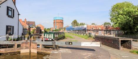 A canal with a lock system, a white building, and a brick structure in the background.