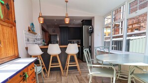 Eine moderne Küche mit Holdekor, ein Essbereich mit Tisch und Stühlen sowie ein Blick ins Freie durch große Fenster.