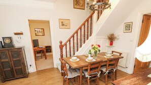 A dining area with a wooden table set for six, a staircase, and a view of a dining room. - Framingham (Hayling Island)