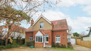 A two-story house with a brick exterior, a tiled roof, and a front garden with a gravel path. - Framingham (Hayling Island)