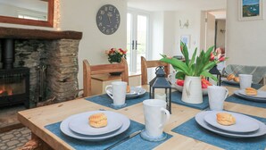 Un coin repas avec une table en bois mise pour le petit-déjeuner, comprenant des assiettes, des tasses et une lanterne.
